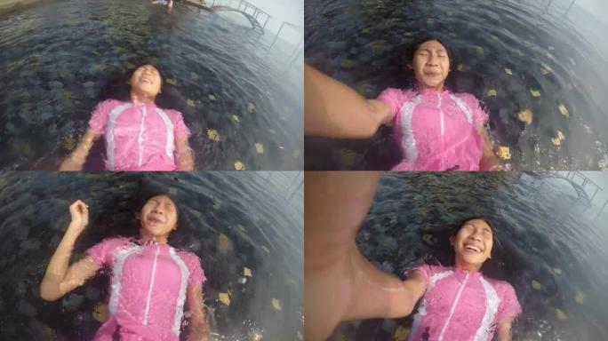 亚洲女孩在阳光明媚的日子里和家人在酒店度假时，回到游泳池里漂浮，生活方式理念。