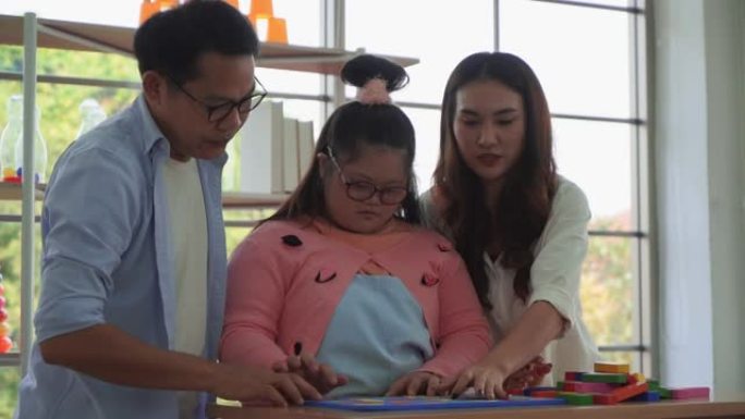 亚洲父母正在协助她的自闭症女儿在家庭中进行教育和发展，以实现特殊的自闭症护理概念。
