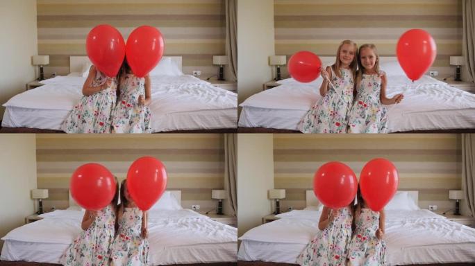 两个双胞胎姐妹坐在卧室的床上，上面放着红色的气球。
