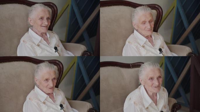 微笑的祖母坐在房间的沙发上，用麦克风说话