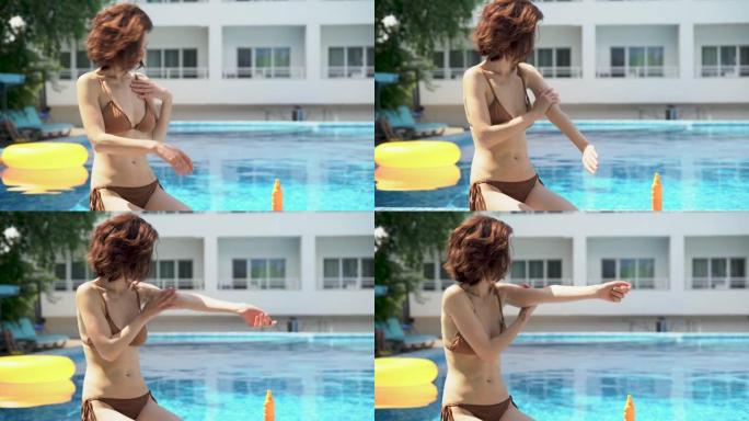 在阳光明媚的夏日，美丽的女人用手在游泳池边晒黑的手上涂抹防晒霜。假期防晒系数。