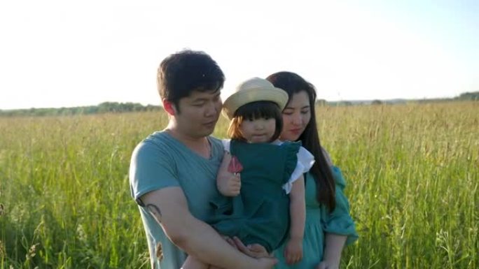 韩国一家人带着女儿在日落时分在草地上