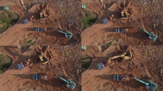鸟瞰式挖掘机在施工现场挖掘土壤并将其装载到卡车上。