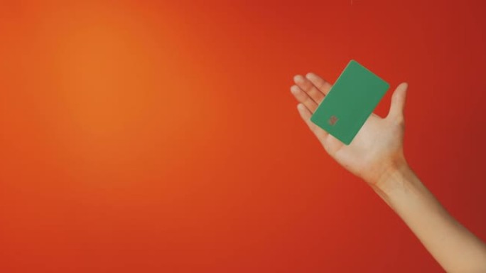 女性手和悬浮模板模拟银行信用卡在线服务孤立在橙色背景