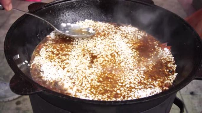 用开槽的勺子在沸腾的乌兹别克抓饭上撒饭