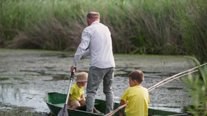钓鱼，祖父和他的孙子在乡下的户外活动中乘船从岸上航行
