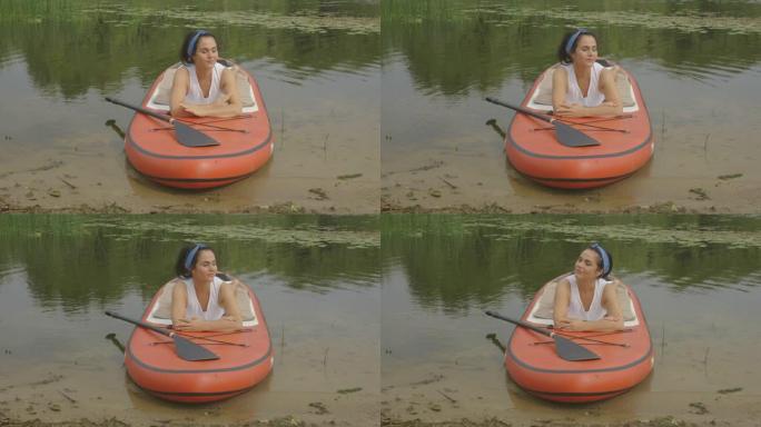 女人在湖边的桨板上晒日光浴