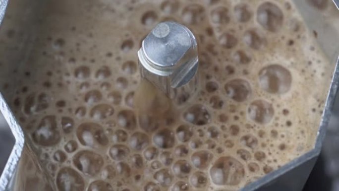 关闭俯视图 (向下倾斜) 新鲜咖啡，从摩卡壶流出的奶油，为早餐准备咖啡杯。