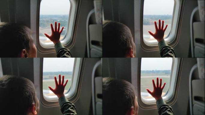 到达机场时，飞机降落时的男孩把手放在窗户上，对风景感兴趣。