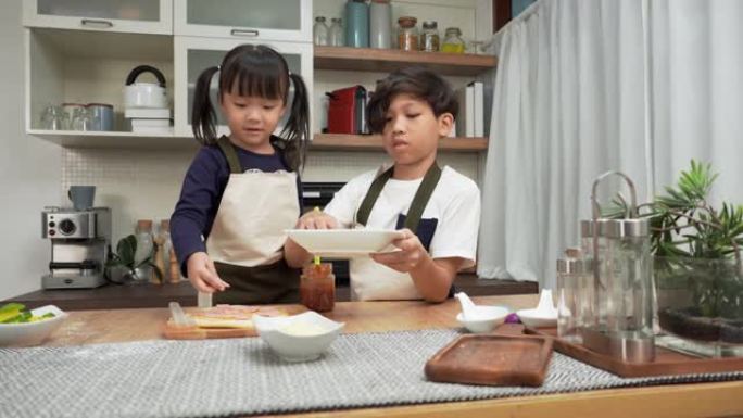 亚洲老大哥，小妹妹有一个有趣的活动来制作比萨饼，在周末添加火腿，甜木饼作为亚洲家庭有两个孩子的晚餐概