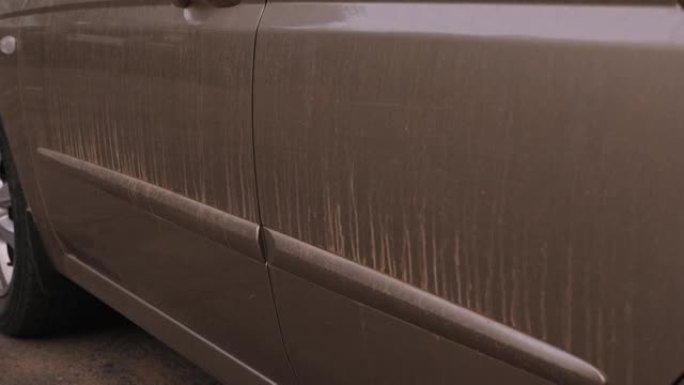 沙尘暴后汽车上肮脏条纹的特写。汽车上的灰尘和污垢。