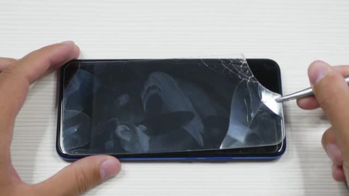 男子从智能手机上取下破损的保护玻璃