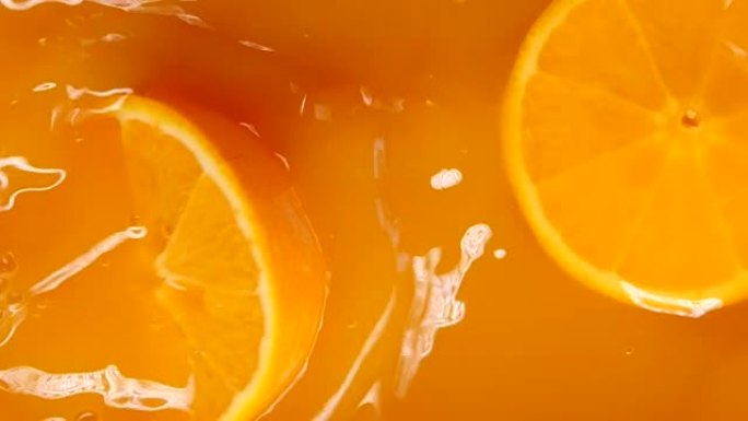 橙子掉落并溅成橙汁，分为两半。新鲜的夏季橙子桌面。水果溅入水中。