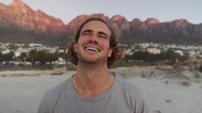 日落时，年轻的高加索男性在海滩上大笑，卷发。高质量4k镜头