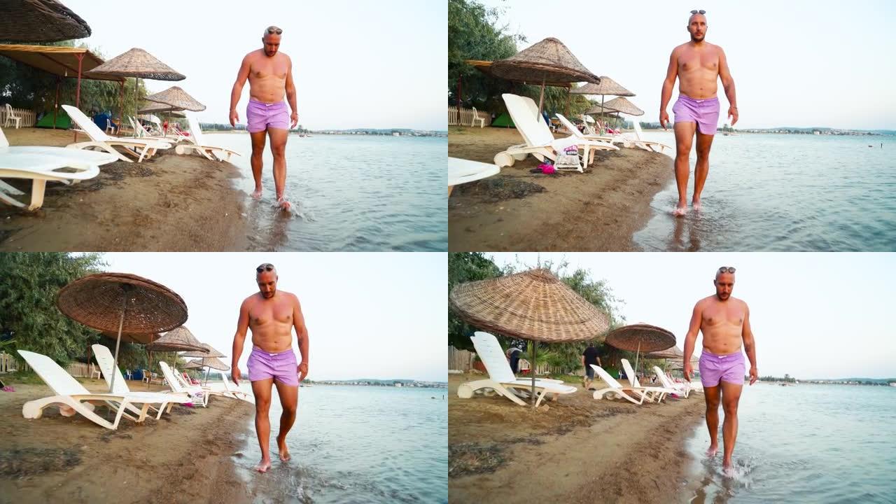 穿着短裤走在沙滩上的4k视频男子