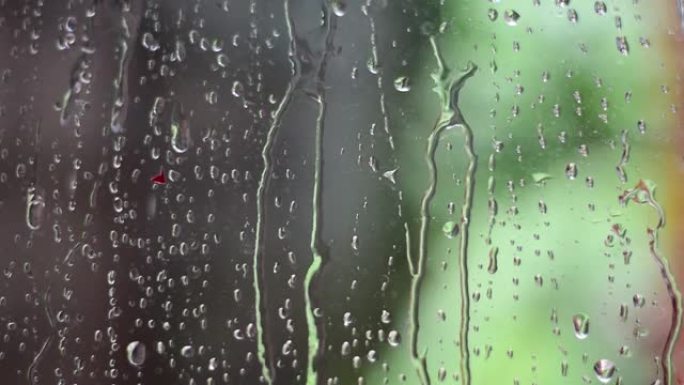 雨水落下，雨水落在透明玻璃上，水慢慢流过透明玻璃。