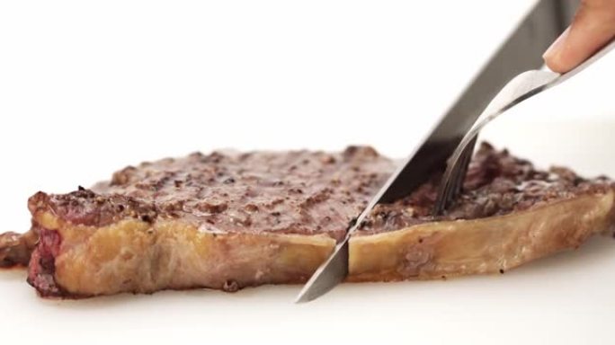 刀叉在白色背景上切割多汁的牛排。