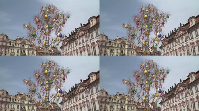 布拉格的一棵五颜六色的复活节树，背景是一些建筑物，巨大的五颜六色的复活节彩蛋以及早午餐上悬挂的五颜六