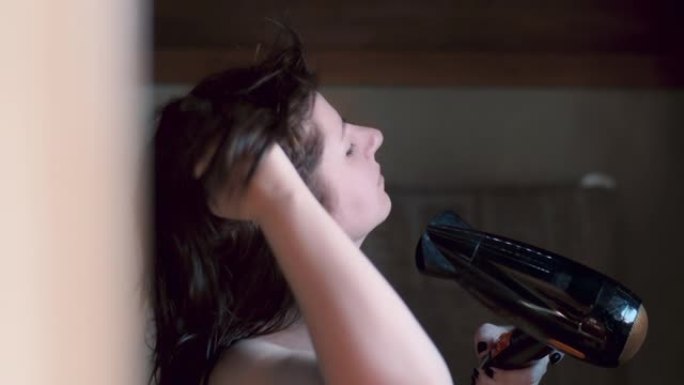 镜子附近浴室里的电影漂亮黑发女人用吹风机吹干头发，头发飘动