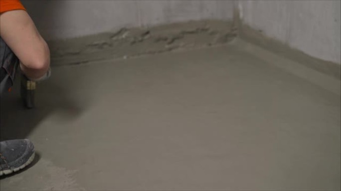 工人用砂浆覆盖混凝土熨平板并进行防水处理。用解决方案对地板进行防水处理的过程