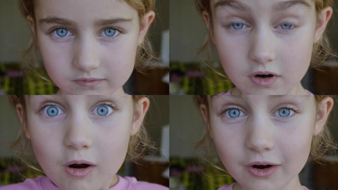小女孩看起来很惊讶，很高兴收到惊喜。蓝眼睛的肖像小孩看着相机特写。惊讶的女孩脸。震惊的儿童表情特写。