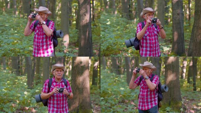 资深男子祖父在徒步旅行中探索野生动物，用复古相机在森林里拍照
