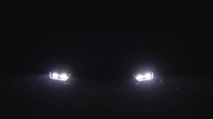 汽车前灯在黑暗中闪烁。跑车前灯。夜间汽车LED大灯的切换