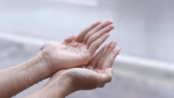 一名女性的手在热带台风引起的雨天玩雨滴，纯雨的春天天气，享受飞溅的纯净水滴，人们触摸大自然，站在路边