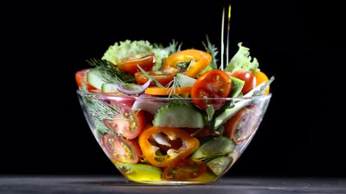 新鲜蔬菜沙拉在黑色背景的玻璃碗中倒入橄榄油。黑魔法Ursa Pro G2，4K，150 fps。