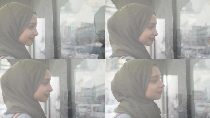 动画的微笑亚洲妇女在希贾布透过窗户看城市风景