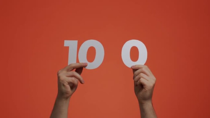 手中的100号。显示数字的人，100由雕刻纸制成的投票或数学学习