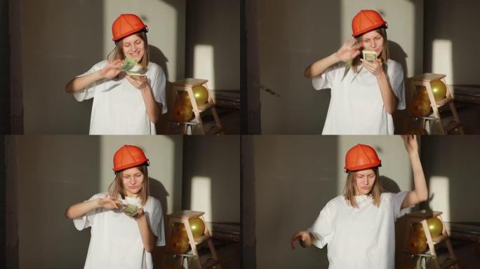 年轻的微笑女工戴着橙色安全帽数钱，站在公寓的建筑工地。建筑师在办公室里扔和玩美元钞票