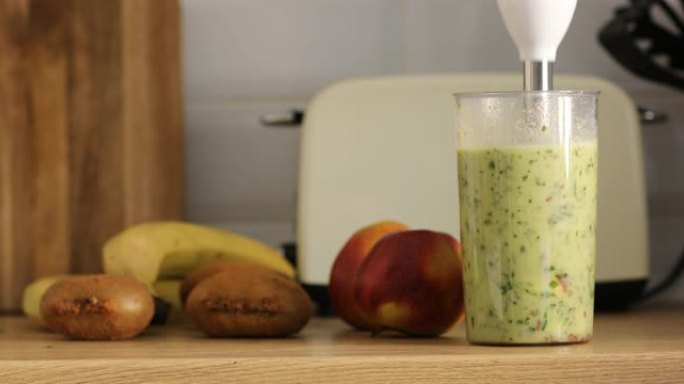 在家里的现代厨房里，用水果和香草搅拌器制作健康的冰沙果汁的裁剪照片。健康饮食，减肥和积极的生活方式和