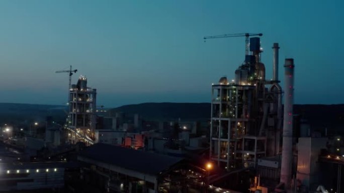 工业生产区高工厂结构的水泥厂，晚上开灯。空中无人机射击