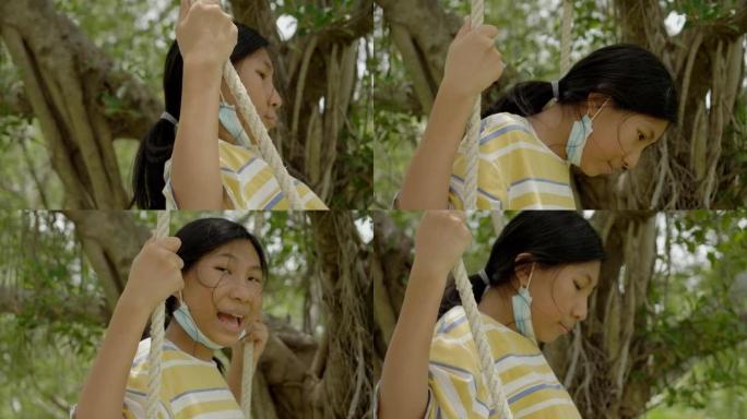 亚洲女孩在户外公园树下玩绳子秋千，生活方式理念。