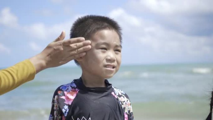 快乐的小男孩暑假站在热带海滩上防晒紫外线