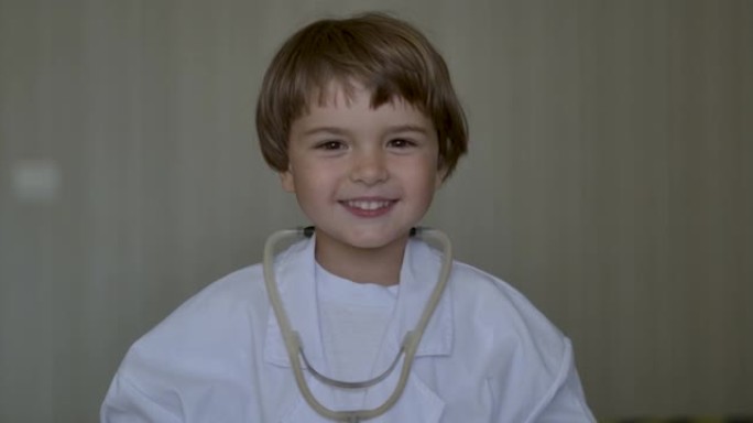 肖像可爱的小男孩穿着医疗制服在家医院玩耍。创意有趣的小男孩穿着医疗制服听诊器玩游戏当医生，假装医生护