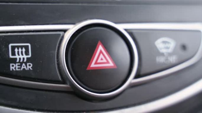 人用手指按下面板上的汽车应急灯按钮，特写。在路上寻求帮助。其他道路使用者的车辆故障通知
