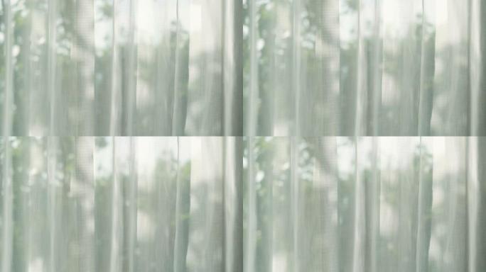 从窗户卧室的窗户透过窗帘的阳光，背后是绿色花园