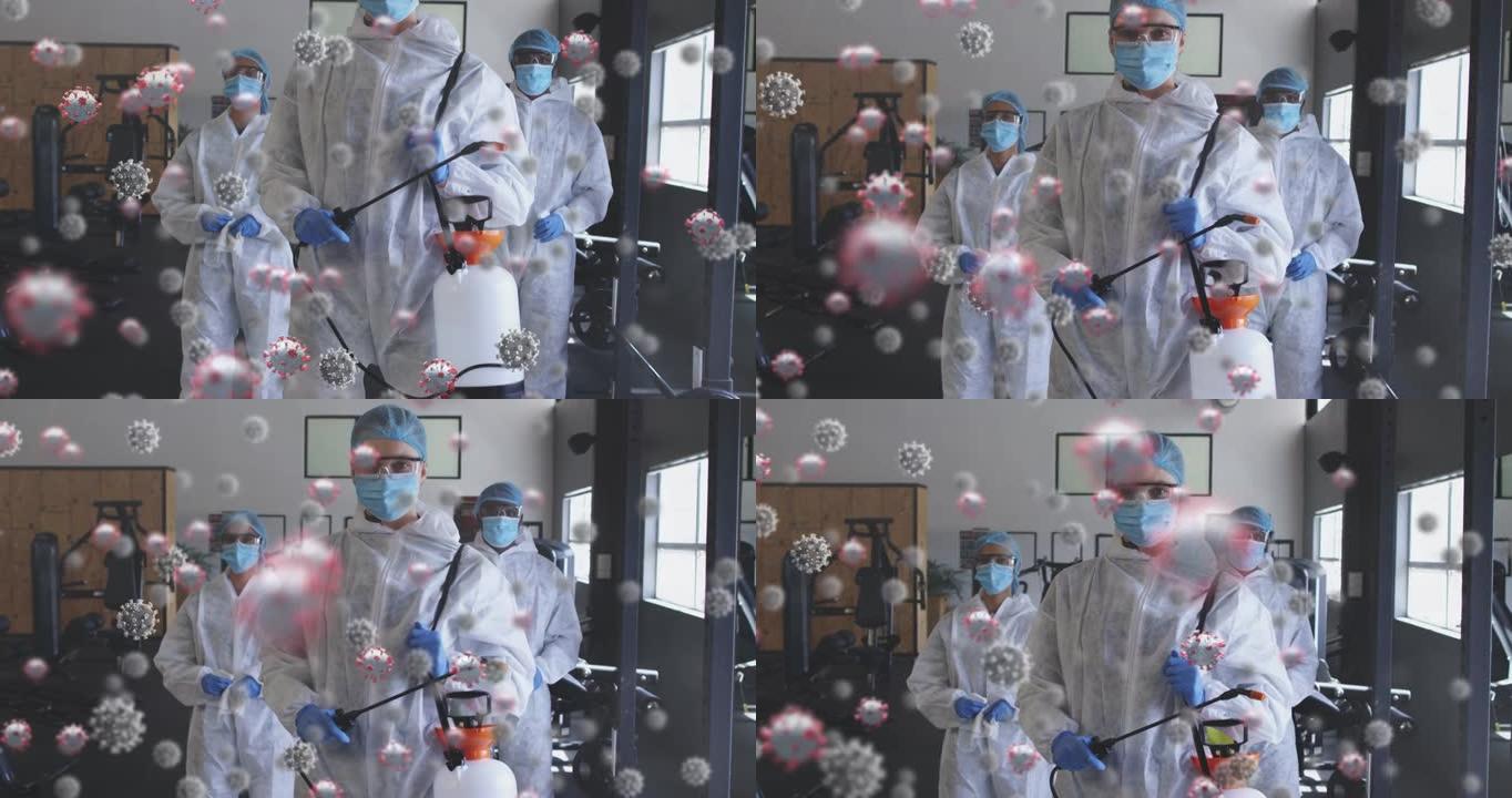 在健身房手持消毒喷雾器的一组卫生工作者上方的多个新型冠状病毒肺炎细胞