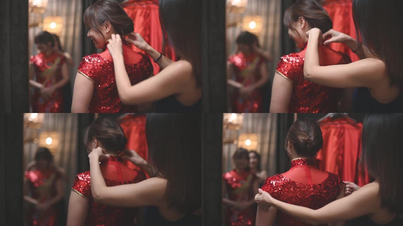 亚洲中国妇女在传统精品店在姐姐的帮助下试穿传统的中国旗袍照镜子