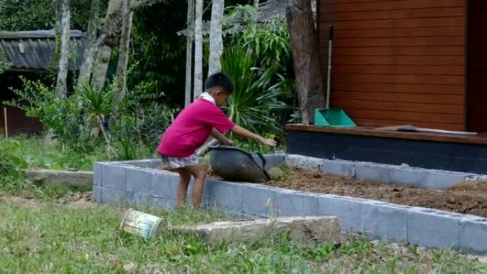 小男孩在建筑工地用桶移动土壤
