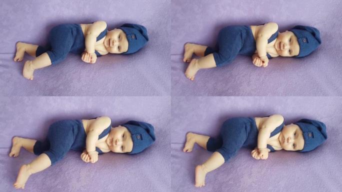 一个穿着蓝色侏儒服装的五个月大的男孩躺在紫色的床罩上