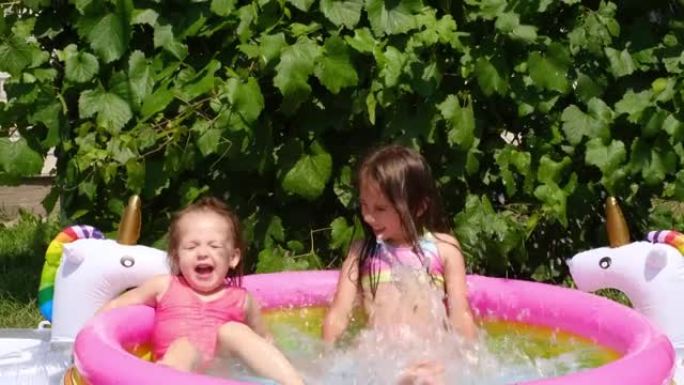 在夏日，女孩们一起在院子里的一个小充气游泳池里跳得很开心。