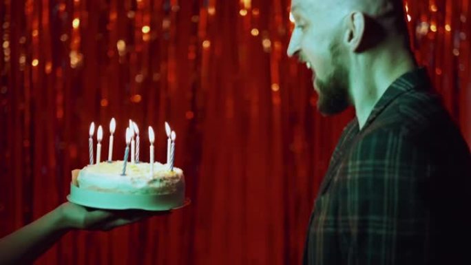 生日快乐兴奋的男人在蛋糕上吹蜡烛
