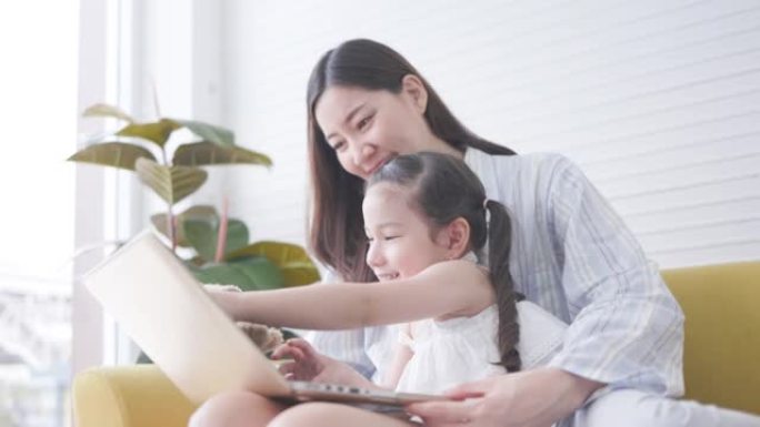 活跃的亚洲母女在客厅家中从平板电脑在线学习。娱乐活动家庭假期。在线教学技术。呆在家里。国家封锁期间的