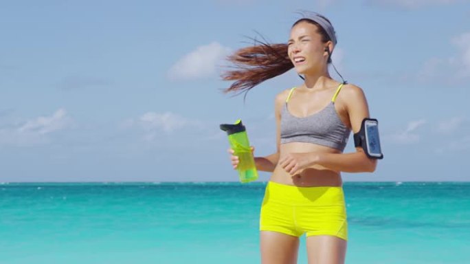有氧运动后疲倦的女跑步者出汗。亚洲跑步女子在锻炼后出汗挥动头部疲惫或触摸额头从瓶子里喝水。衰竭/脱水