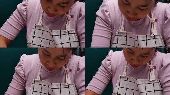 围裙中的女人在不锈钢容器中揉面面团，为制作自制比萨饼准备面团。烹饪过程。
