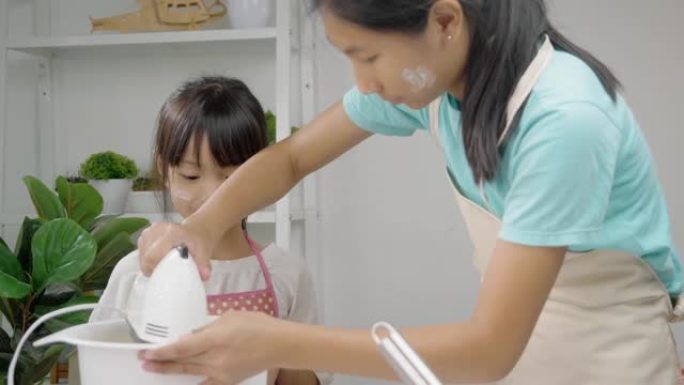 亚洲女孩在家和妹妹一起搅拌面团自制饼干，生活方式理念。
