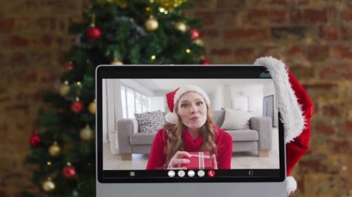 快乐的白人妇女在计算机上进行视频通话，带有圣诞节装饰品和树木